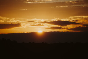 Obraz premium Scenic orange sunset in the clouds over the forest