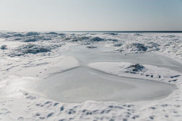 Smooth ice and snow on a frozen beach in winter
