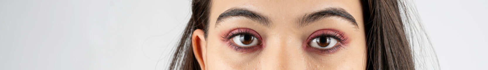 Obraz premium Macro shot of woman eye makeup with red eyeshadow. Close-up of woman eyelashes. Panoramic shot.