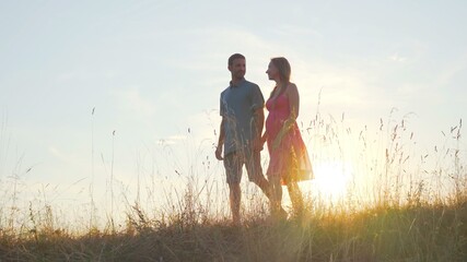 A friendly large family walks across the field at sunset.