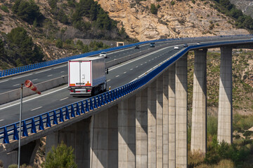 Refrigerated truck driving over a long bridge and next to a windsock.