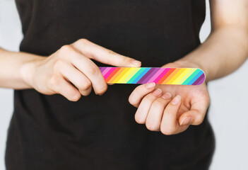 A young girl files her nails with a colored nail file close-up. Nail care. Filing nails on the...