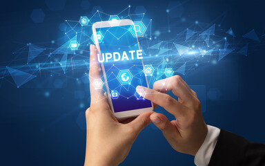 Female hand holding smartphone with UPDATE inscription, modern technology concept