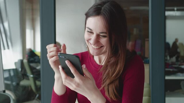 Excited young woman hold phone chatting in dating app feel happy sit on hair, euphoric overjoyed lady winner celebrate mobile online bid game win victory success receive read good news on cellphone