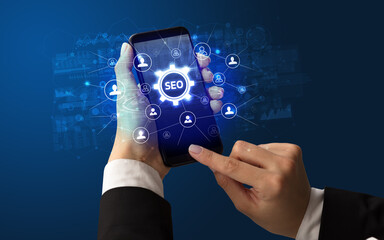 Female hand holding smartphone with SEO abbreviation, modern technology concept