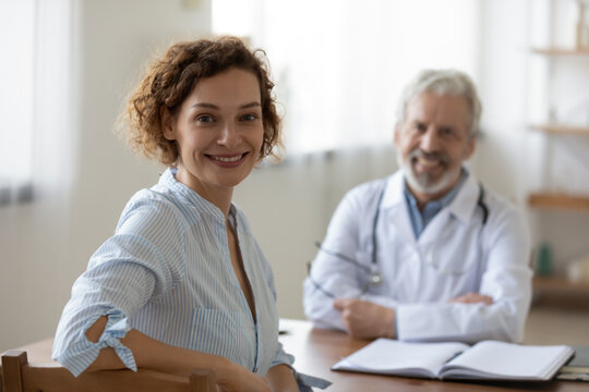 Portrait of happy young female patient sit in private hospital satisfied with good medical service. Smiling woman client look at camera feel excited after consultation in clinic. Healthcare concept.