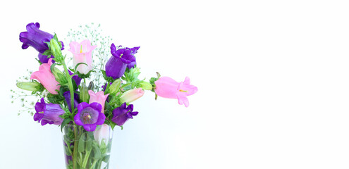 spring bouquet of purple, white and pink bell flowers over white wooden background