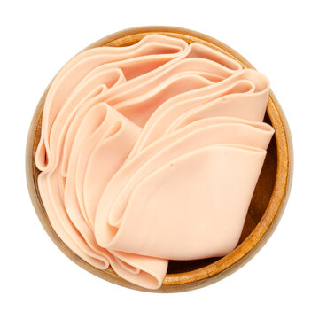 Vegetarian sausage, cold cut, in a wooden bowl. Thin slices of meatless Extrawurst, similar to Lyoner or Bologna sausage. Scalded protein of milk, egg white and peas. Isolated over white, food photo.