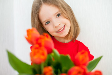 Beautiful girl in a bright red turtleneck holding a bouquet of red tulips. High quality photo
