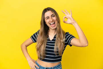 Young caucasian woman isolated on yellow background showing ok sign with fingers