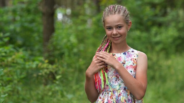 Teenage girl with multi-colored dreadlocks in the forest.