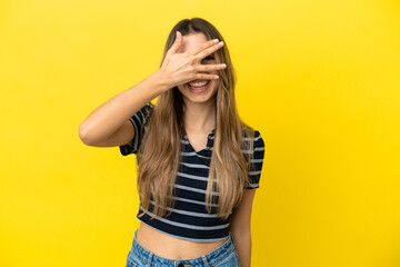 Young caucasian woman isolated on yellow background covering eyes by hands and smiling