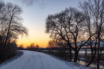 Beautiful orange blue sunset over a snowy road. Winter landscape.