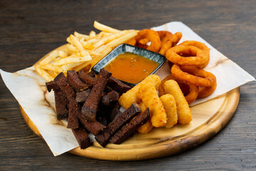 assorted fries of croutons, potatoes, nuggets and onion rings with mustard sauce. beer snack is junk food. pub menu