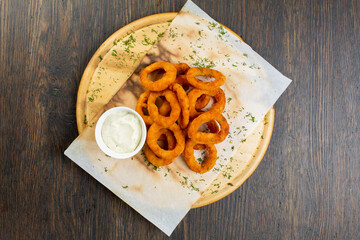 deep-fried onion rings in breading with creamy sauce. beer snack. view from above
