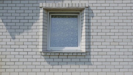 A lonely window in a white brick house.