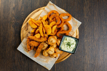 assorted fries of onion rings, French fries, chicken nuggets and fried dumplings with creamy sauce