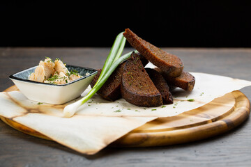 pate with black bread croutons with green onions on a wooden board