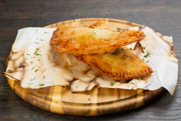 deep-fried pasties with pork and beef. piroshki with meat and herbs on a wooden board