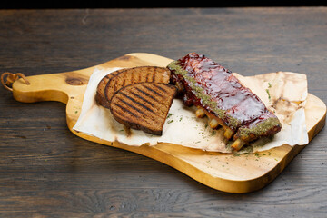 grilled pork ribs with barbecue sauce and grilled bread slices. pork with tomato spice sauce on a wooden board