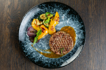 grilled minced beef cutlet with grilled vegetables and barbecue sauce. fried zucchini, onion and pepper with minced pork cutlet