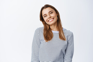 Image of cheerful good-looking woman tilt head and smile at camera friendly, looking joyful and...
