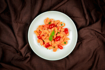 Top view macaroni pasta with tomato sauce, pork and vegetables.