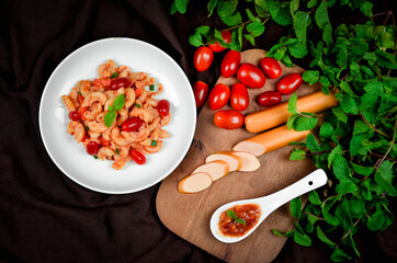 Top view macaroni pasta with tomato sauce, pork and vegetables.