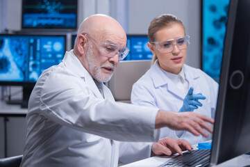 Obraz premium Professor and his young and professional laboratory assistant are doing scientific experiment in a modern laboratory. Genetic engineers workplace. The concept of science, medicine and vaccine.