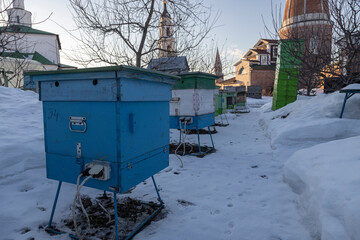 hives in winter on the territory of the monastery. multi-colored hives in the snow. Colored bee...