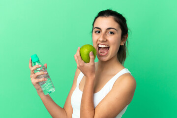 Young caucasian woman isolated on green background with an apple and with a bottle of water