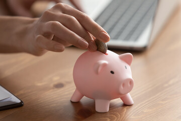 Crop close up of woman put coin into piggybank save money for future, make investment. Female feel...