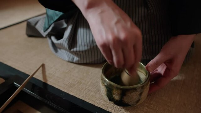 Cultural heritage of Japan: traditional Japanese tea ceremony. Tea master mixing matcha tea in chawan bowl with the use of special tools: chasen, chashaku, Chaki. One of the practices of Zen Buddhism