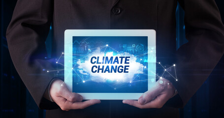 Young business person working on tablet and shows the inscription: CLIMATE CHANGE