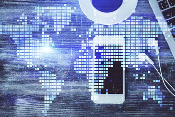 Double exposure of business theme hologram over desktop with phone. Top view. Mobile international...