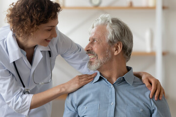 Obraz premium Caring Caucasian female nurse support caress optimistic overjoyed senior Caucasian man patient. Smiling woman doctor comfort mature male during home visit. Elderly healthcare, geriatrics concept.