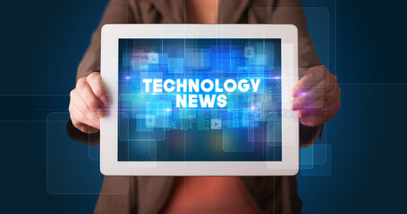Young business person working on tablet and shows the inscription: TECHNOLOGY NEWS