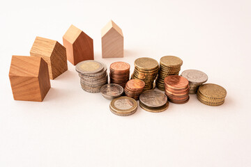 Coins and wooden models of tiny houses represent financial growth, real estate financing and investing in real estate.