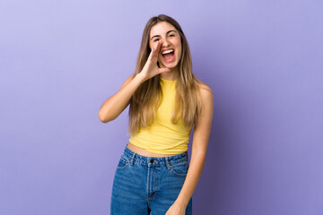 Young woman over isolated purple background shouting with mouth wide open