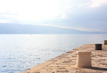 Fototapeta premium Empty stone wharf in the harbor with concrete moorings in Senj, Croatia. View of the Adriatic Sea 