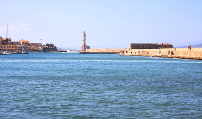 Fototapeta na wymiar A harbor bay at the old Venetian harbor of Chania on Crete, Greece. View of the stone breakwater and the lighthouse 