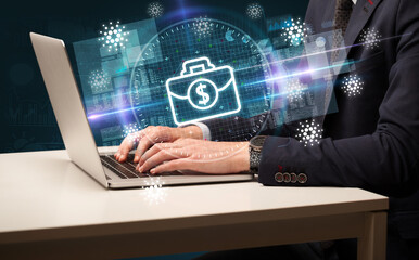 business hand working in stock market with briefcase icons coming out from laptop screen