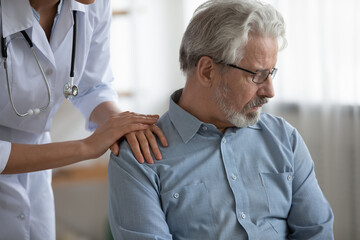 Caring female nurse touch support upset mature Caucasian male patient feeling lonely depressed....