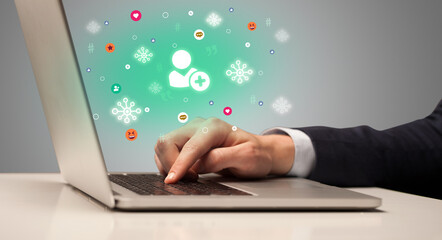 Hand surfing on the social media with friend request icons coming out from the screen, networking concept