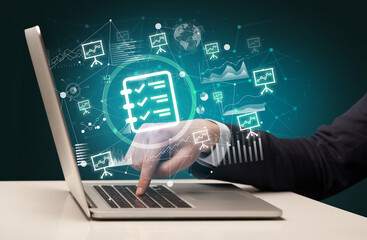 Business hand working on laptop with checklist icons coming out from the screen, successful business concept