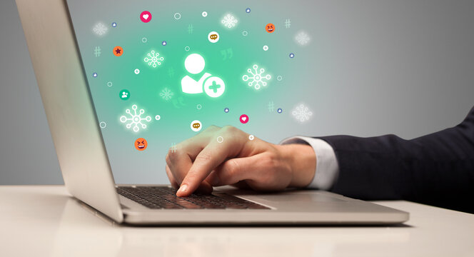 Hand surfing on the social media with friend request icons coming out from the screen, networking concept