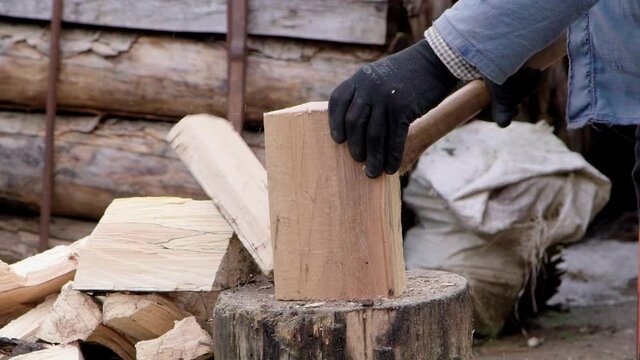 a man chops firewood with an ax in the yard. Close-up slow motion.