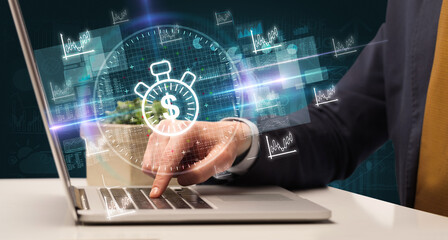 business hand working in stock market with time is money icons coming out from laptop screen