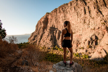 Naklejka premium rear view of attractive woman standing on stone and enjoying on view of mountain landscape.