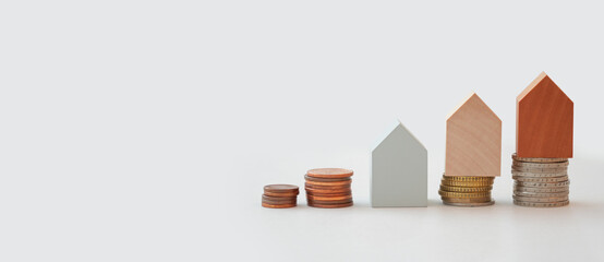 Coins and wooden models of houses represent financial growth, real estate financing and investing...